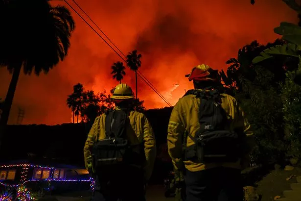 Uma visão do incêndio florestal enquanto aviões e helicópteros de combate a incêndios jogam água sobre as chamas no Mandeville Canyon